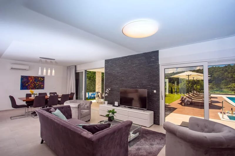 Un salón con TV y salida a una piscina y a una zona de comedor exterior.