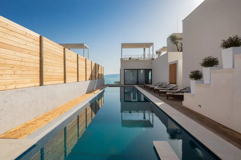 Heated private swimming pool with hydromassage bench, sun deck, lounge area, and outdoor shower