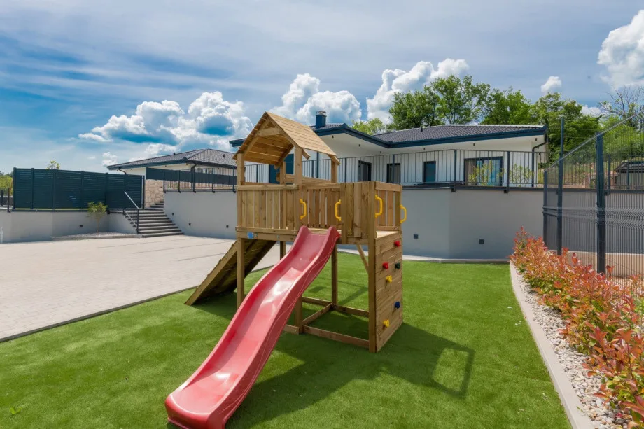 Casita de juegos de madera con tobogán y columpio.