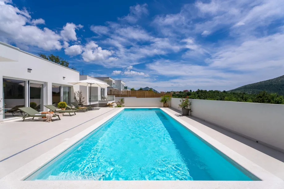 Pool sun deck with six deck chairs and umbrellas