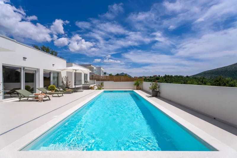 Terraza junto a la piscina con seis tumbonas y sombrillas