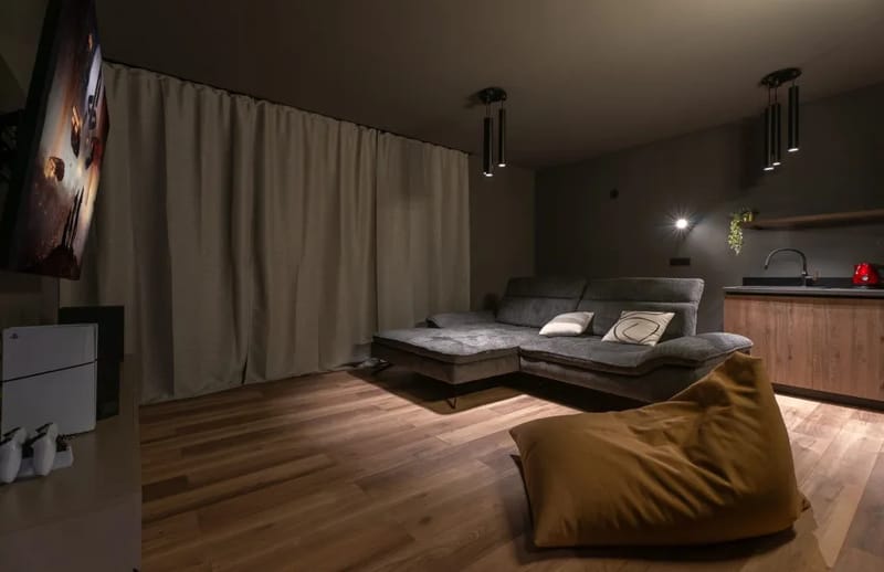 Sala multimedia con aire acondicionado, sofá, TV, PlayStation 5 y minibar