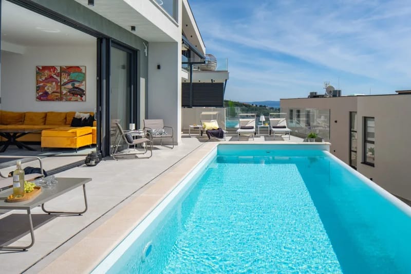 Puertas de cristal de suelo a techo que integran la zona de estar y la zona de la piscina