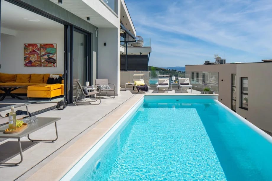 Puertas de cristal de suelo a techo que integran la zona de estar y la zona de la piscina