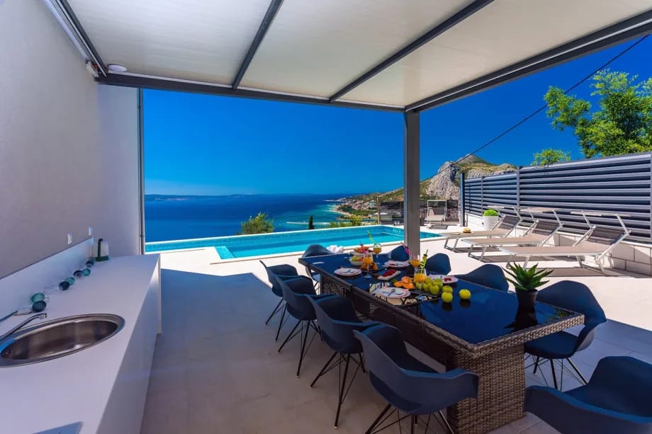 Cocina de verano totalmente equipada con parrilla y zona de comedor exterior cubierta
