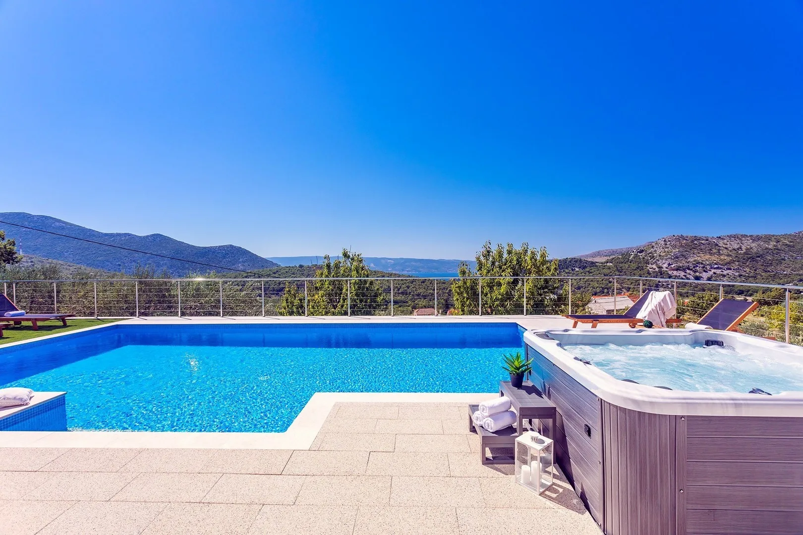 Outdoor pool area with a raised hot tub beside the pool.