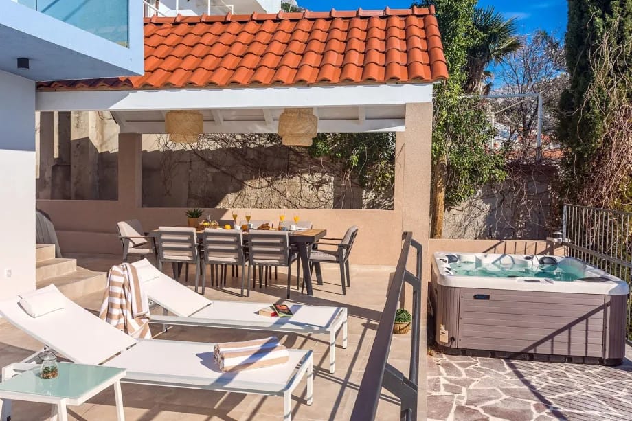 Zona de comedor cubierta para 8 personas con barbacoa eléctrica, rincón de descanso y ducha exterior.