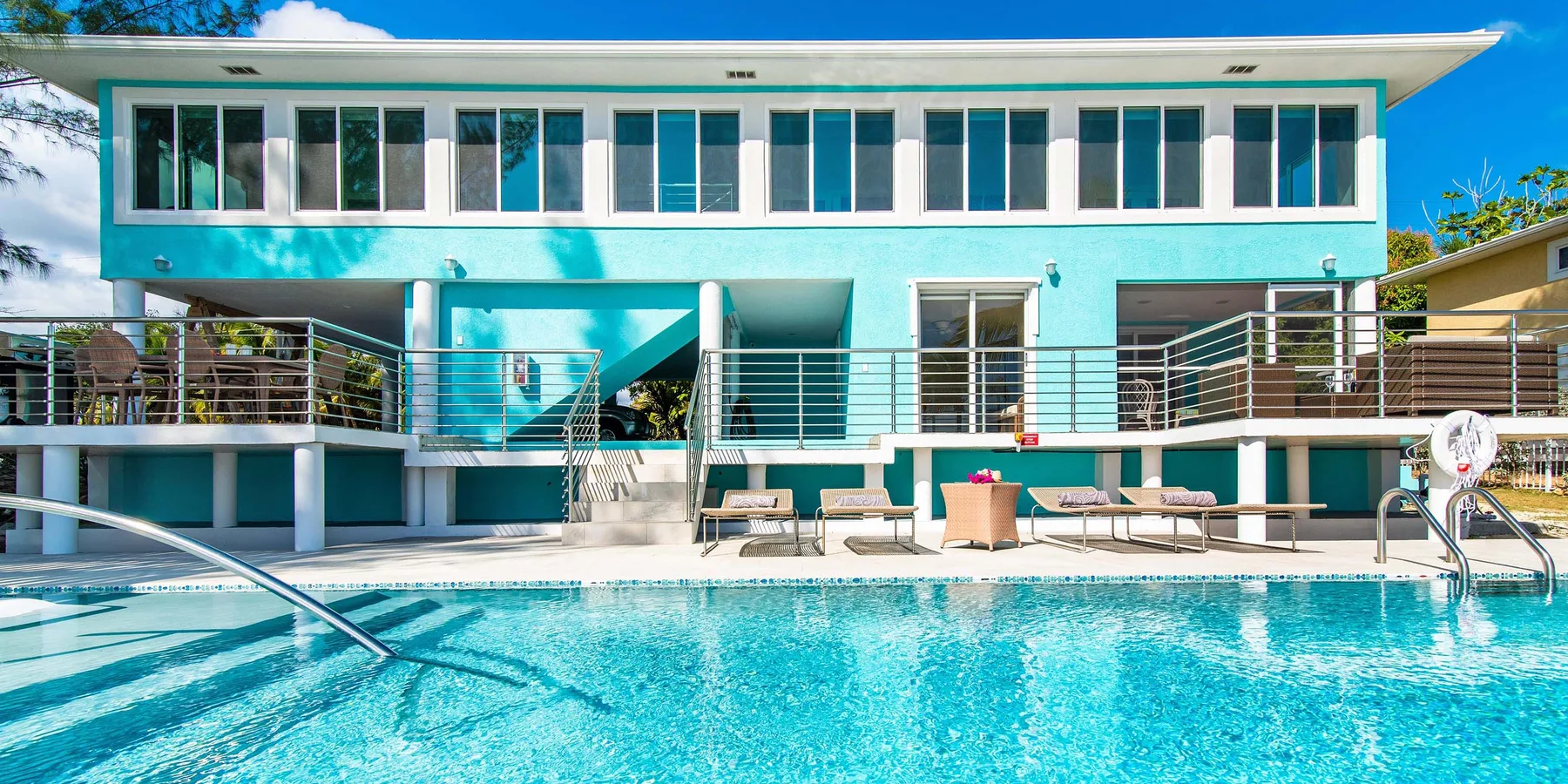 Una piscina está frente a un edificio moderno con un balcón.