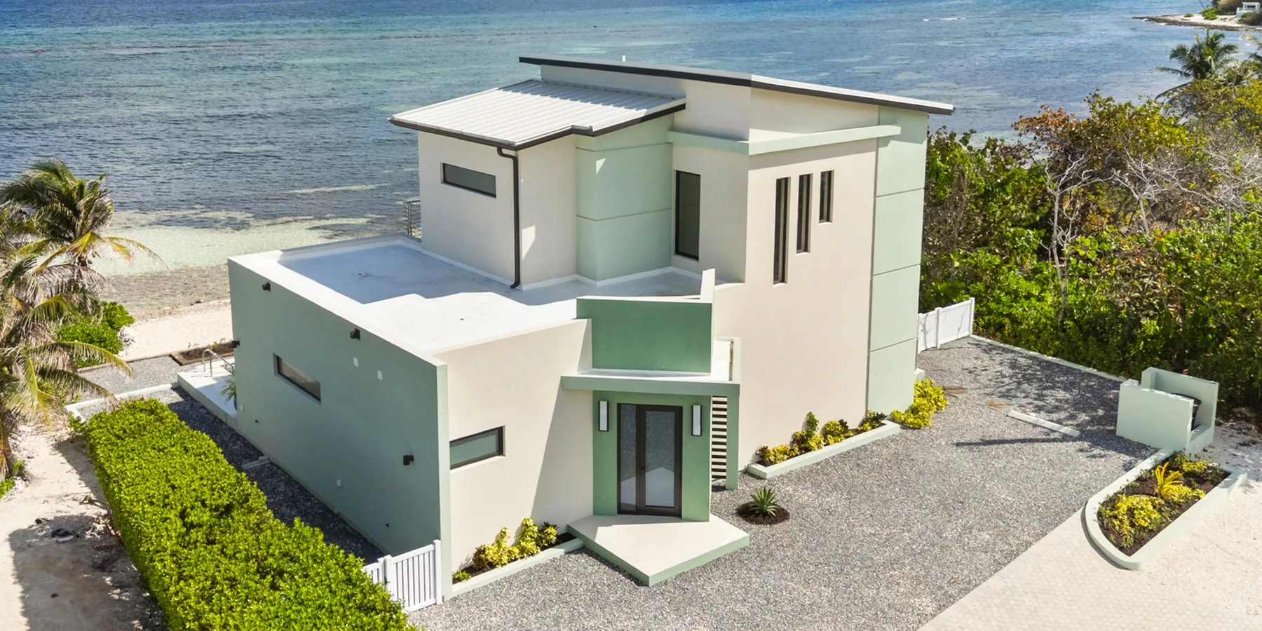 Una casa costera moderna con paredes blancas y entrada de grava.