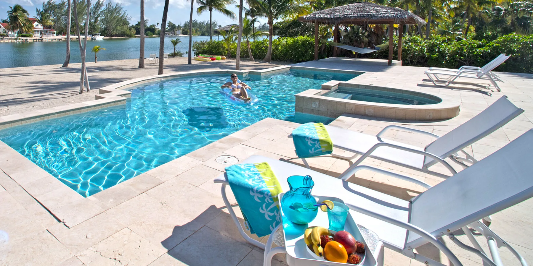 A swimming pool beside a waterfront, with lounge chairs on the surrounding deck.