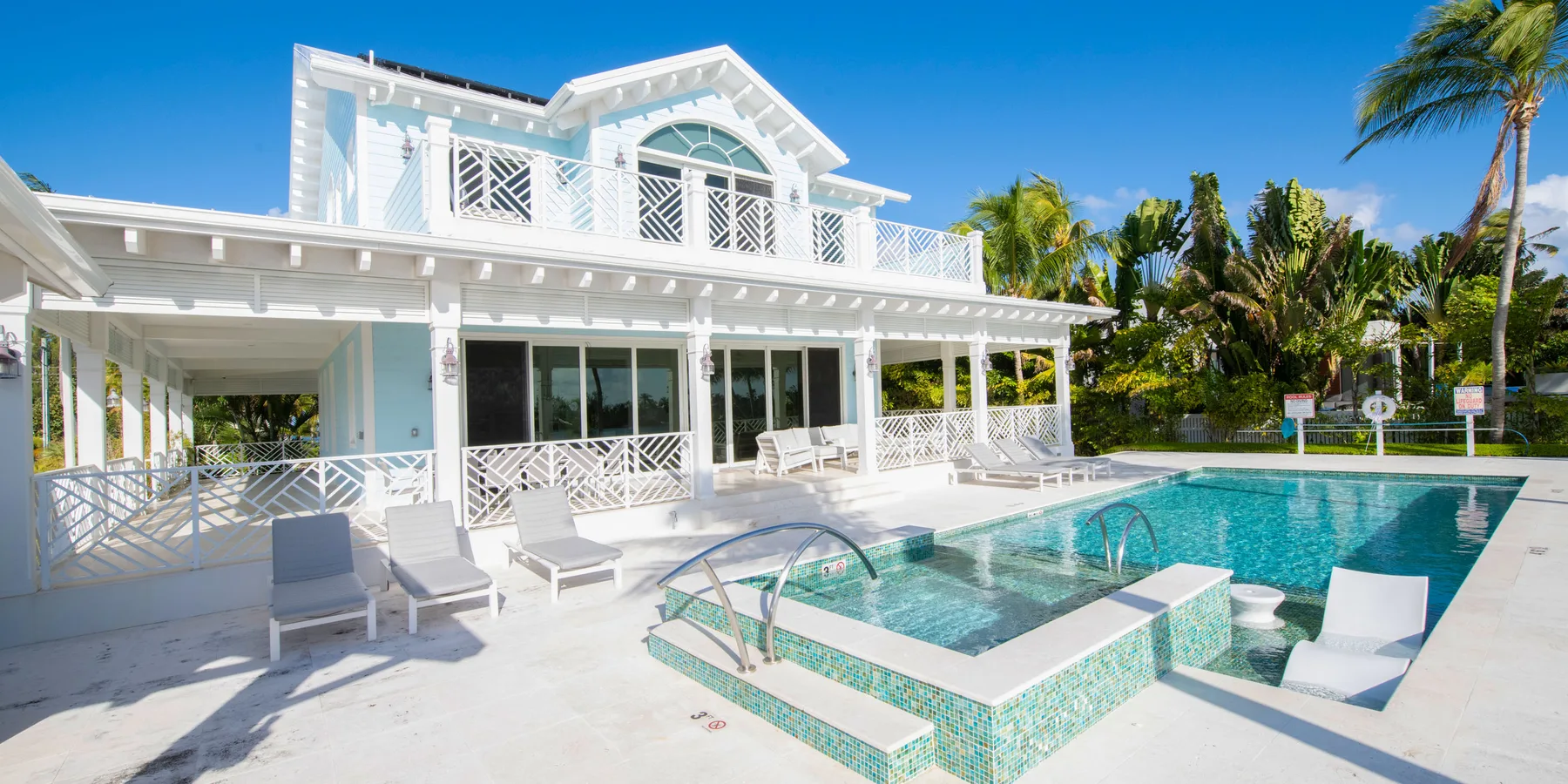 Una casa blanca y una piscina están rodeadas de palmeras.
