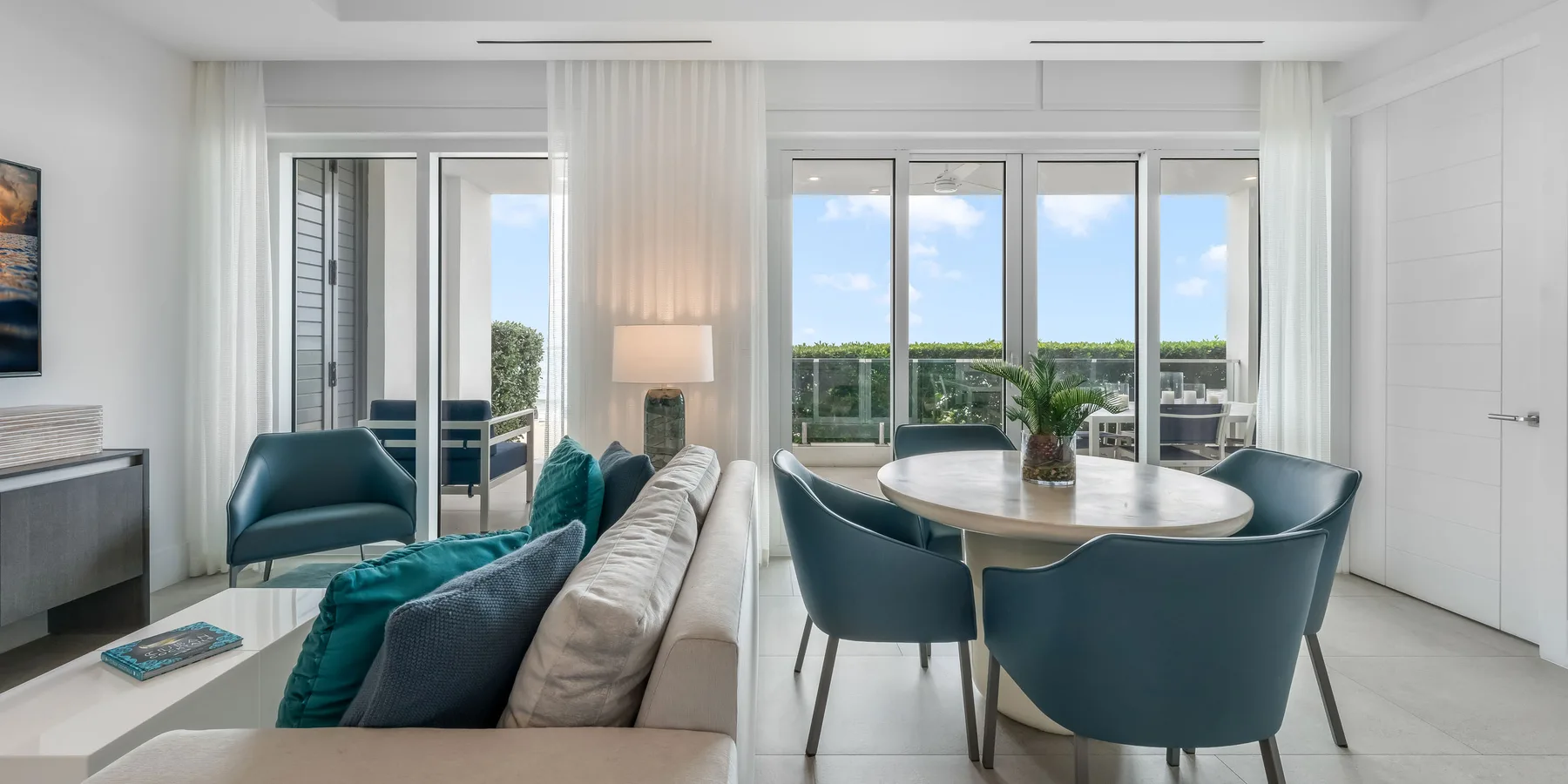 Un comedor y sala de estar luminosos con una mesa redonda y asientos azules.