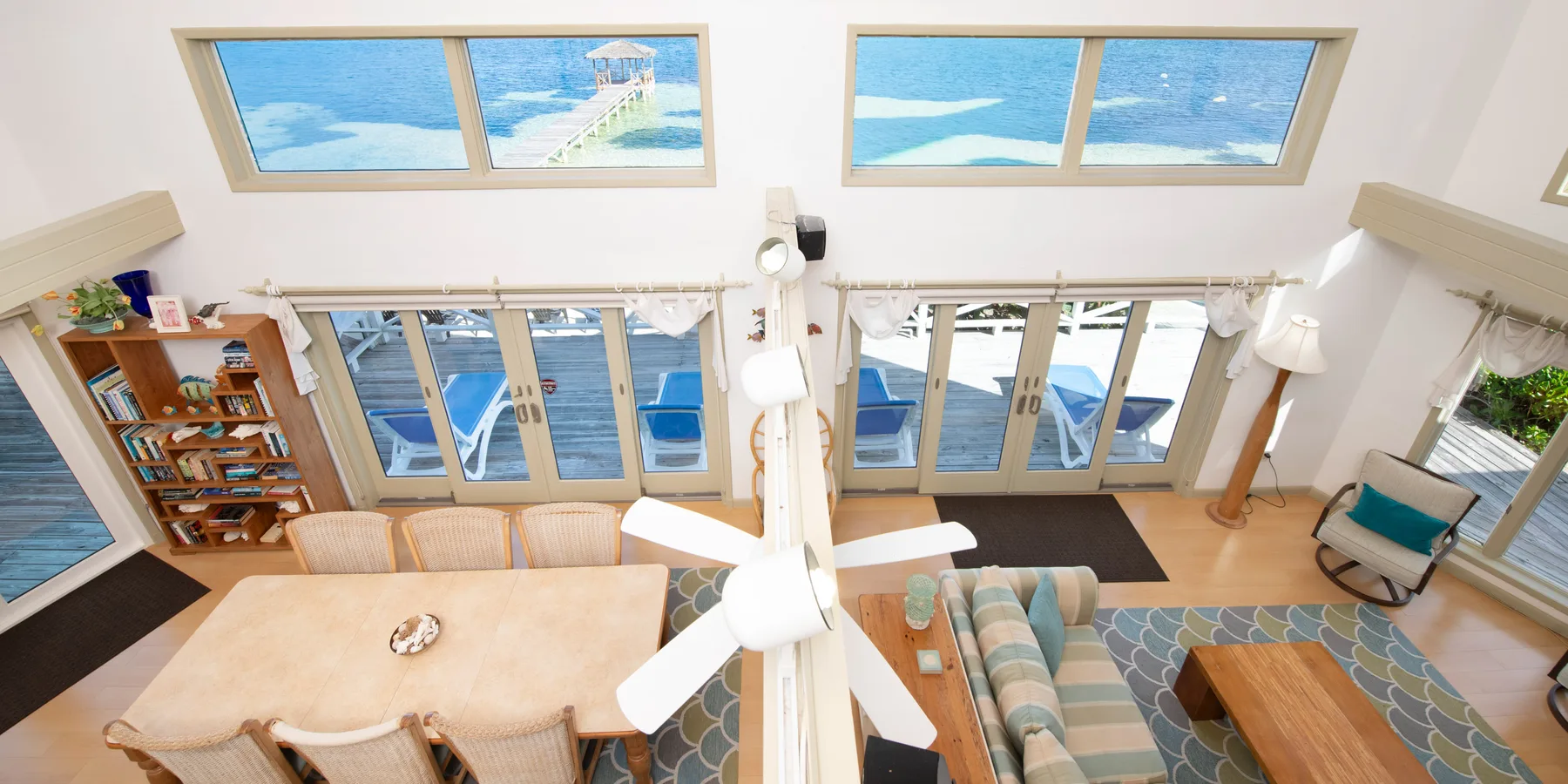 Una luminosa sala de estar y comedor tiene grandes ventanas con vistas al océano.
