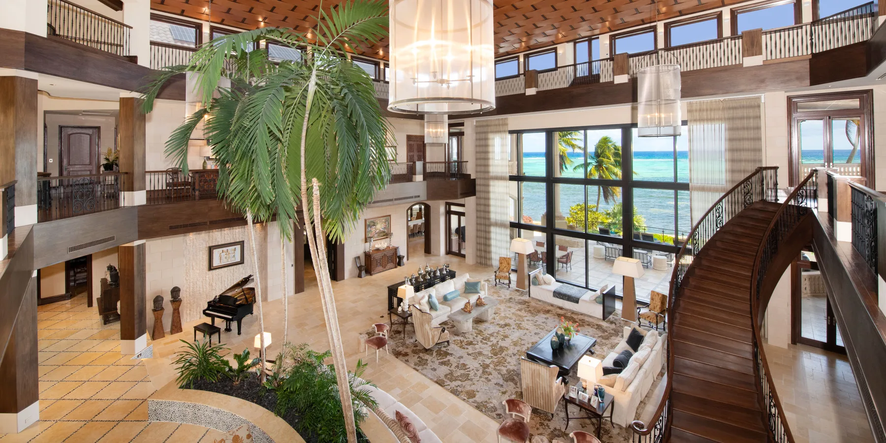 Una amplia sala en un atrio con una palmera alta y grandes ventanas.