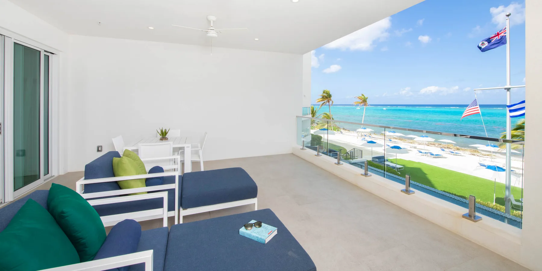 Una sala abierta con asientos azules y una barandilla de vidrio frente al mar.