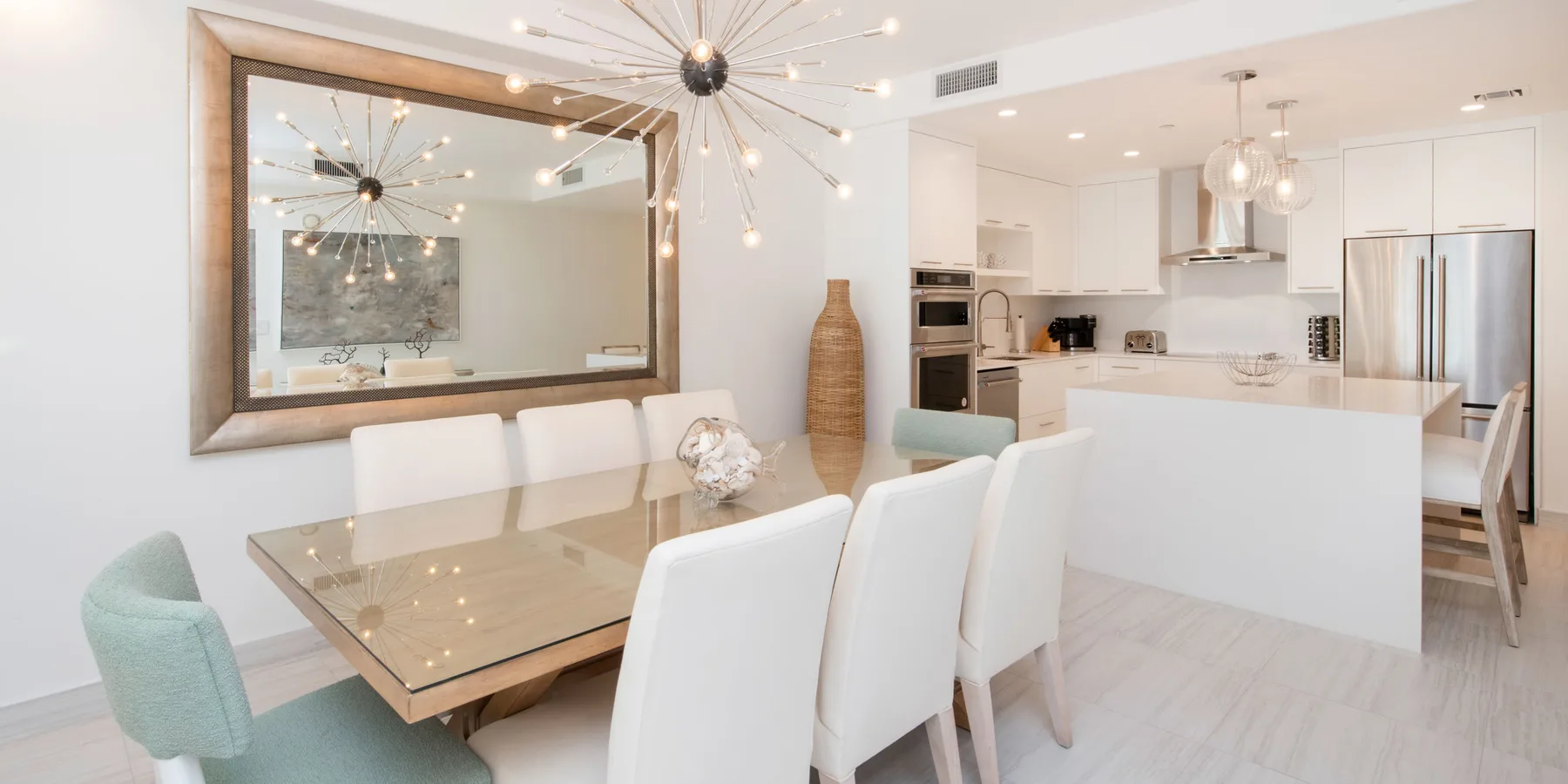 Una zona abierta de comedor y cocina con una mesa grande y luces colgantes.