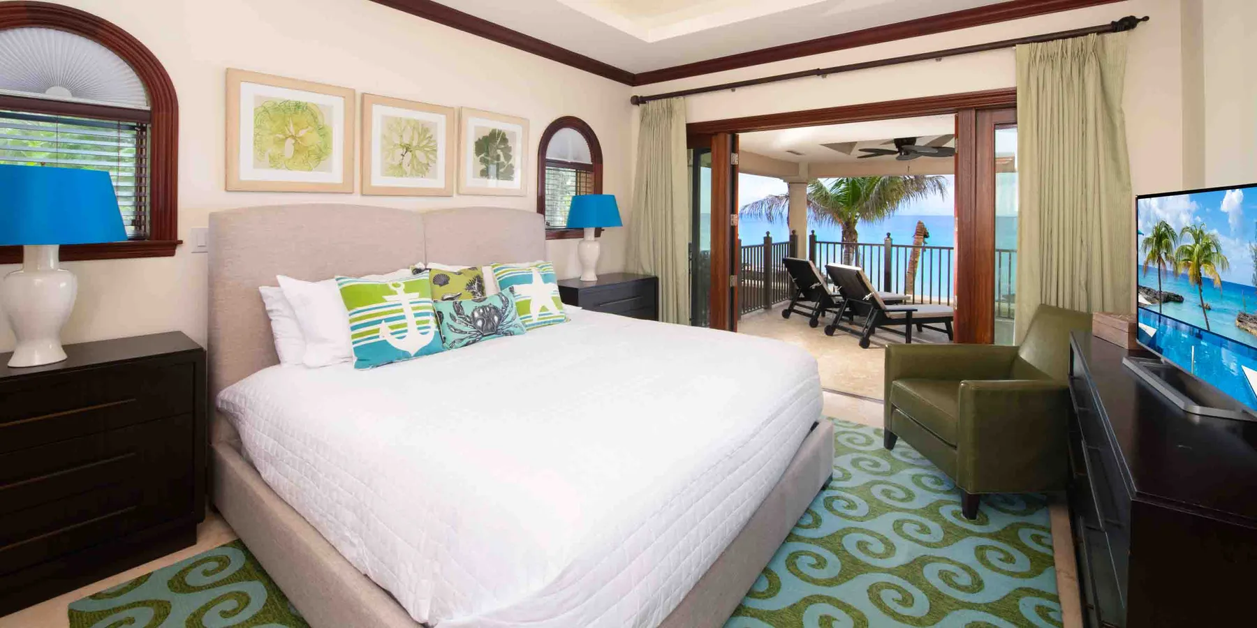 Un dormitorio con una cama bien tendida y vistas al mar a través de las puertas abiertas.