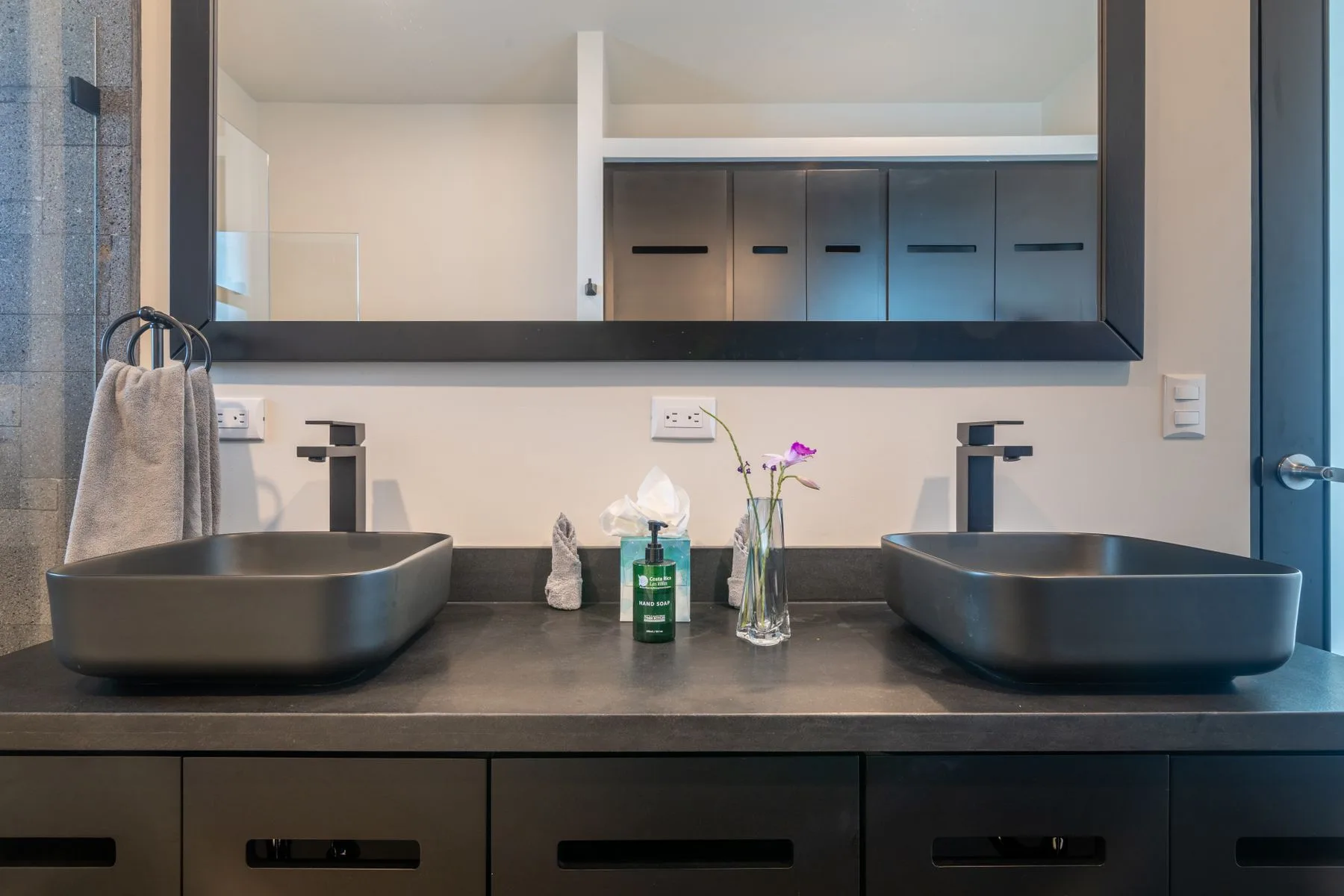 A bathroom vanity with two vessel sinks beneath a large mirror.