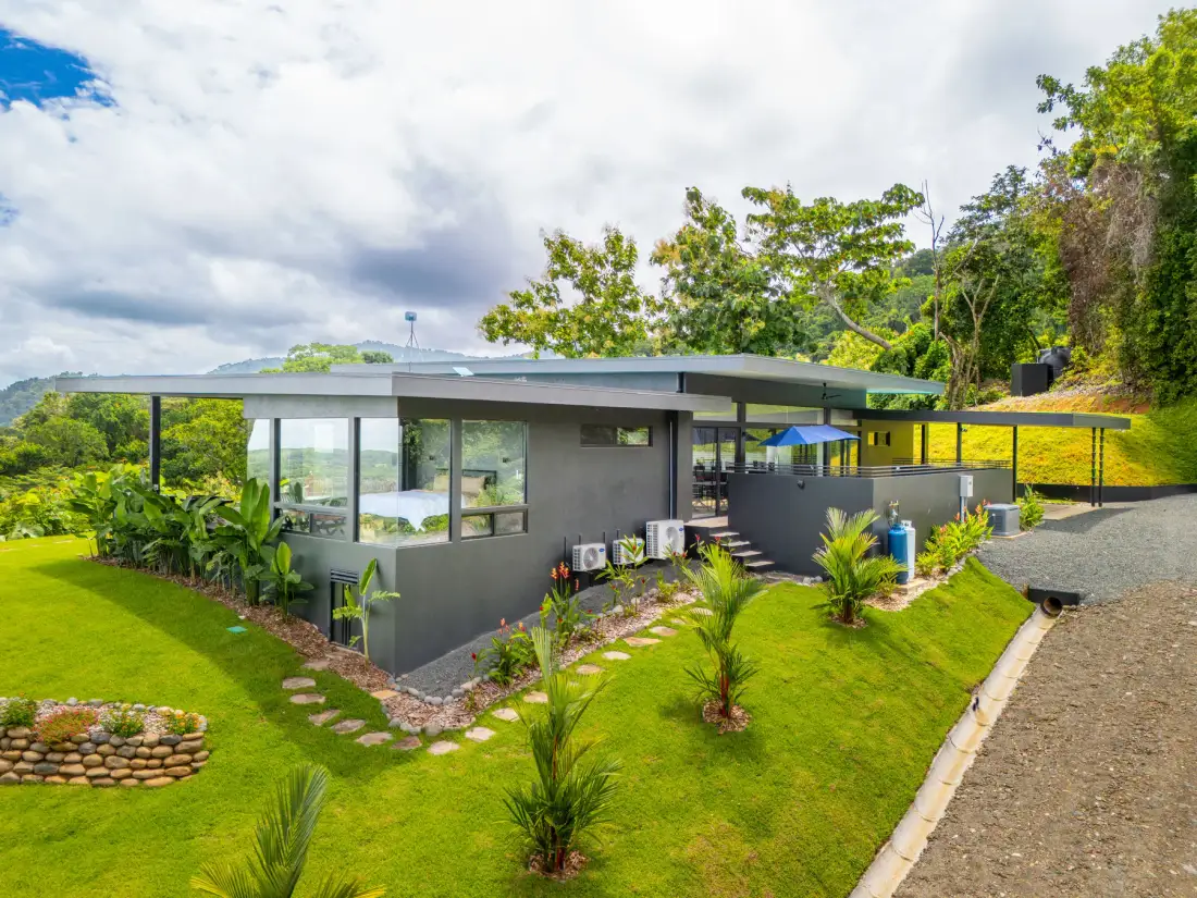 A modern low-rise building sits amid a landscaped green lawn and trees.