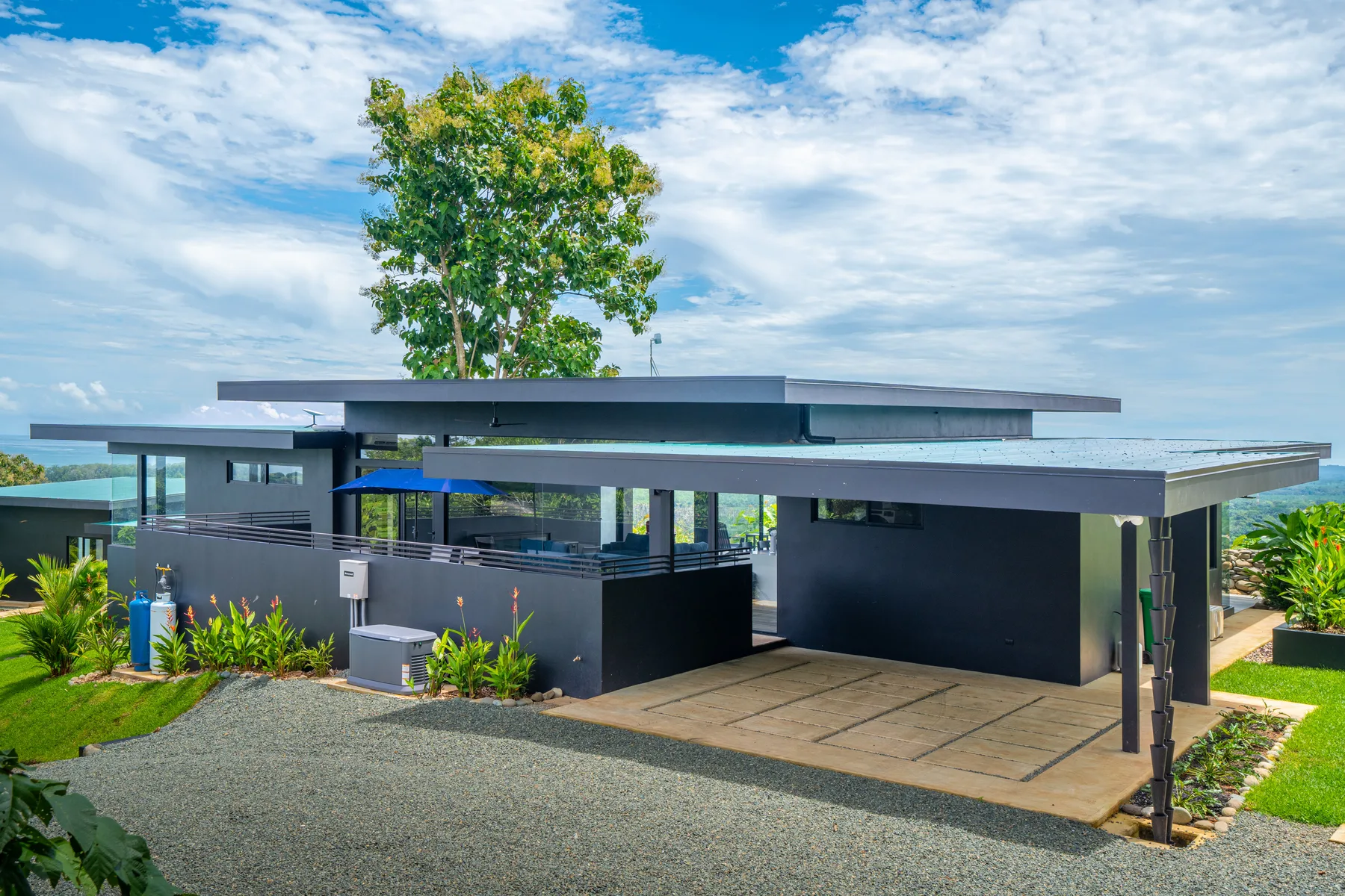 A modern low-rise building with a broad paved entrance and landscaped greenery.