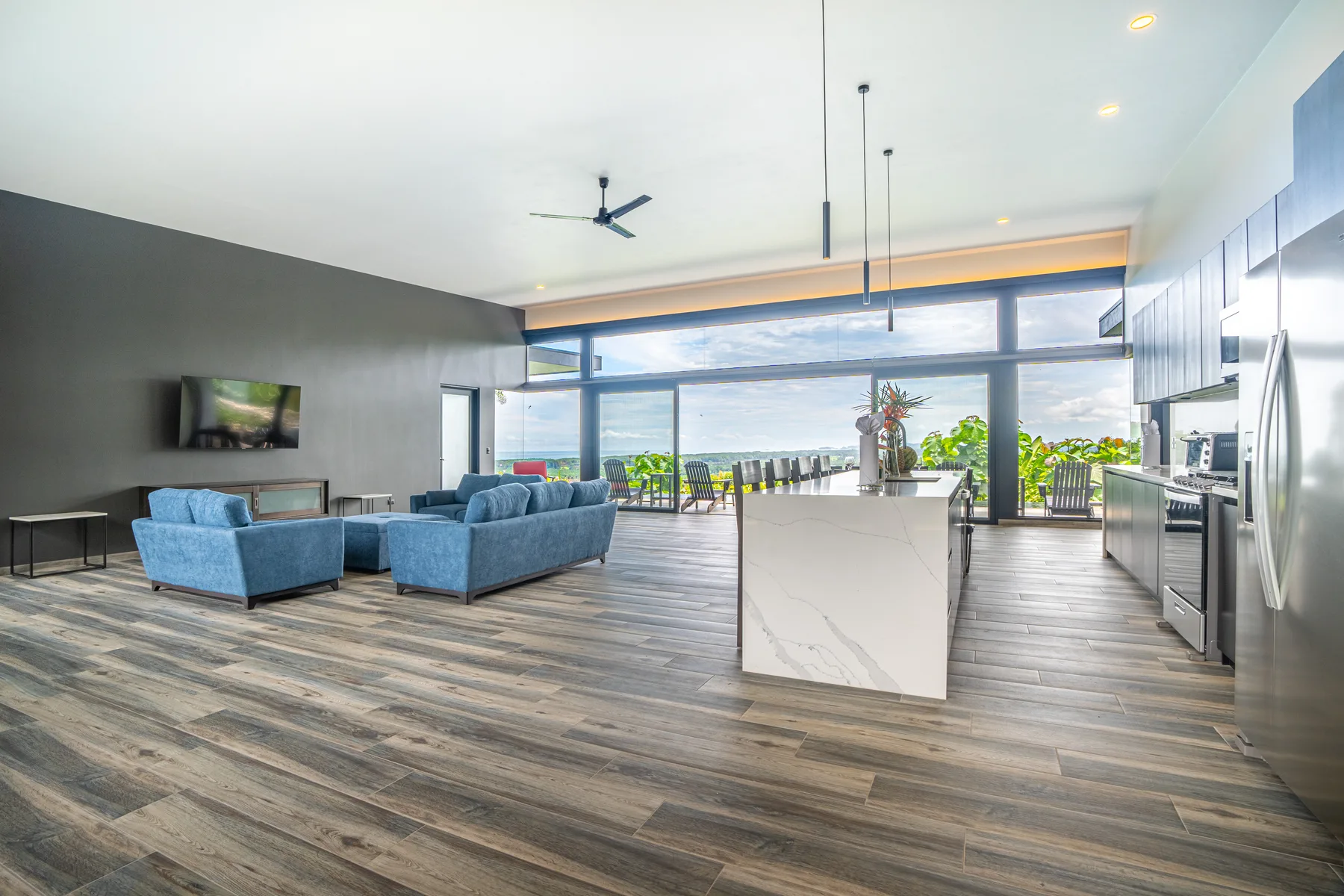 An open-plan living room and kitchen with blue seating and a central island.