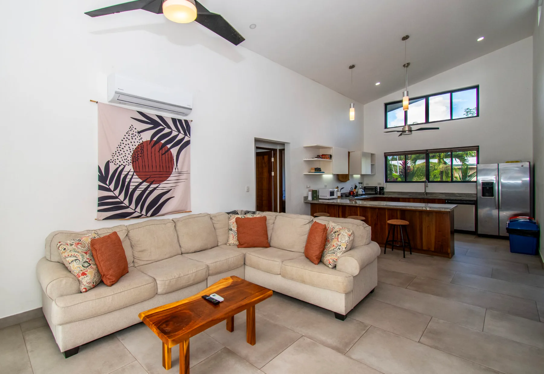 A bright open-plan living room with a sectional sofa and kitchen.