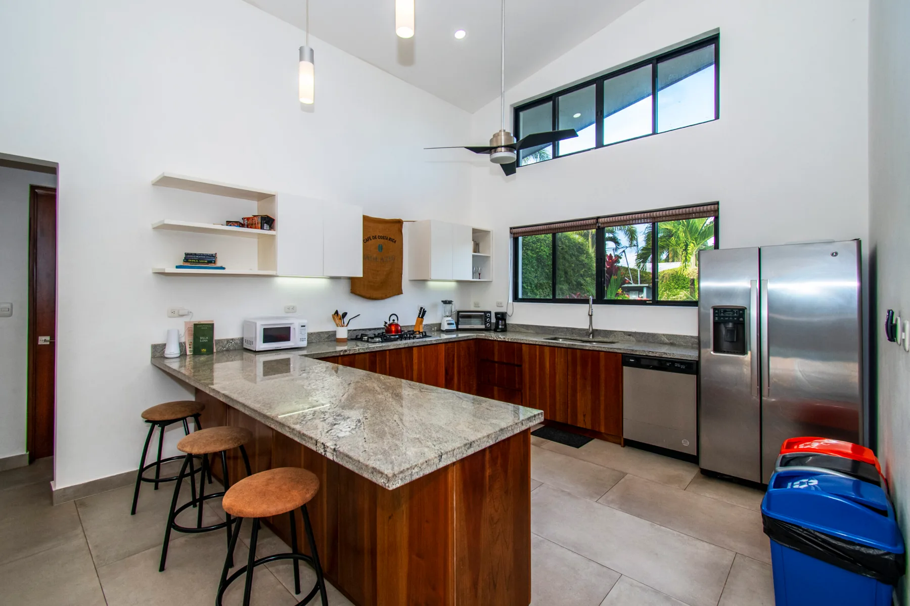 A spacious kitchen with a stone island, wood cabinetry, and stainless steel appliances.