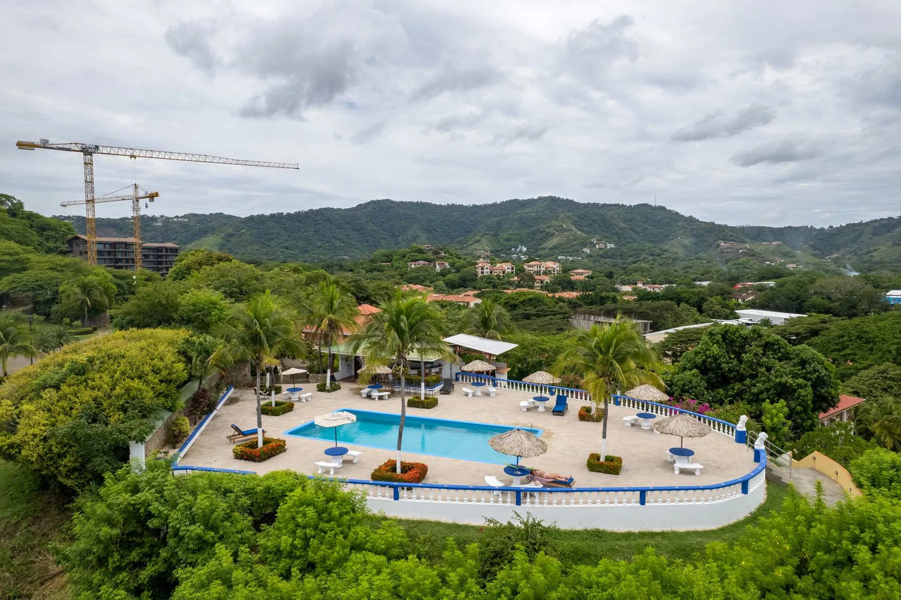 An outdoor swimming pool with surrounding seating overlooks green hills.
