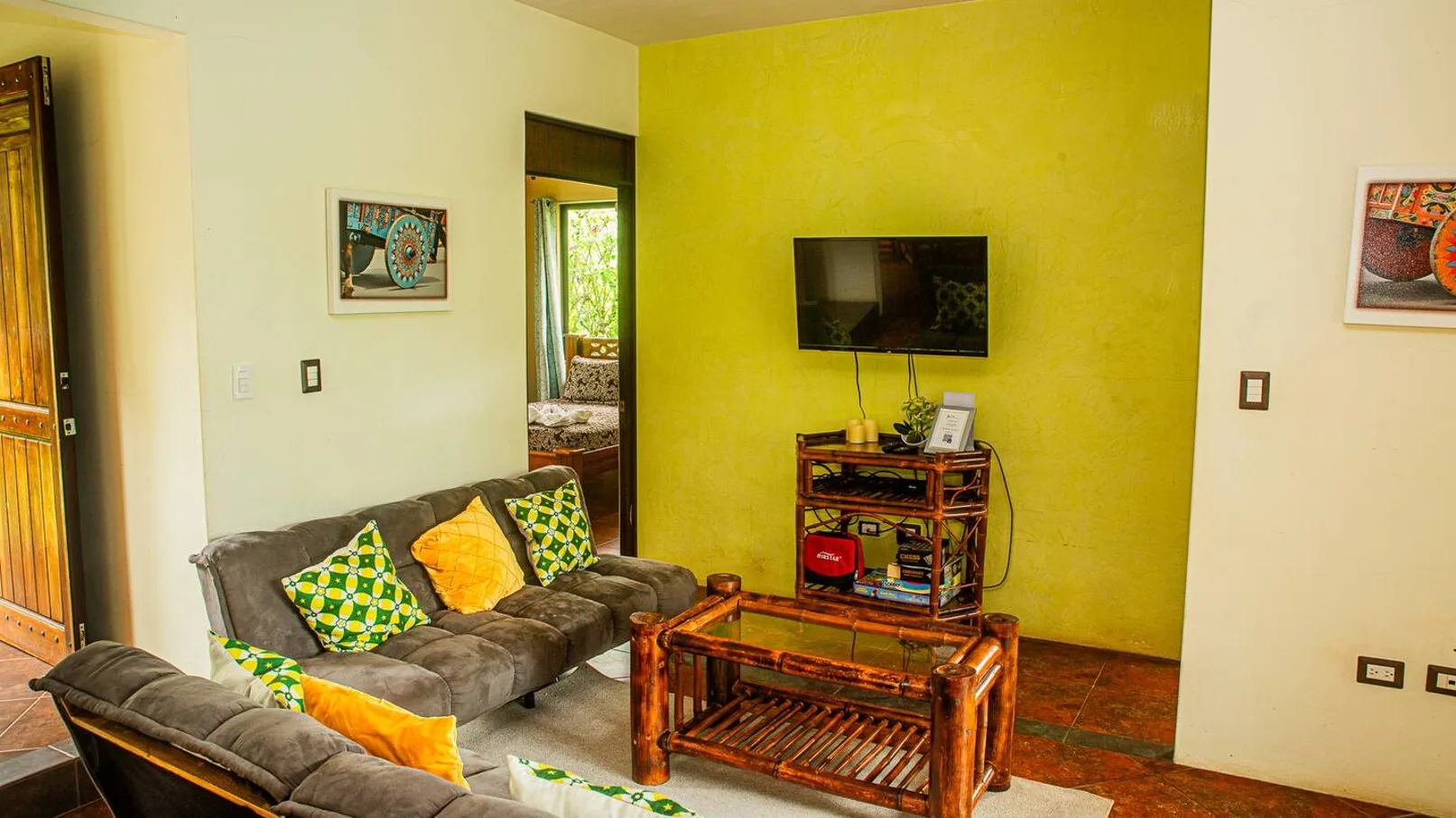 A living room with seating and a television against a yellow accent wall.