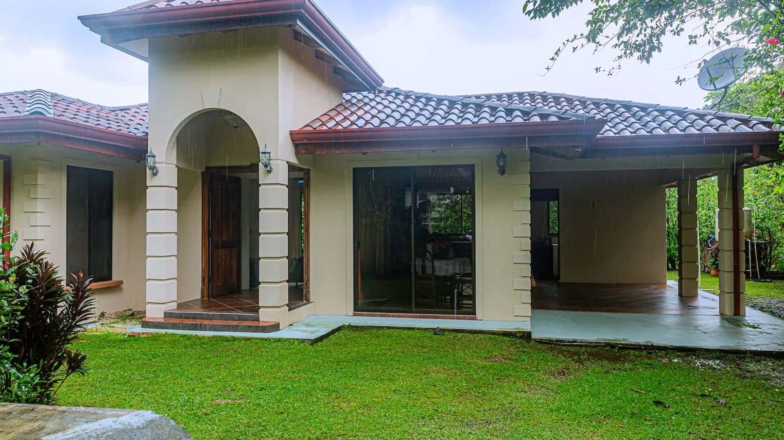 A single-story house with a tiled roof faces a green lawn.