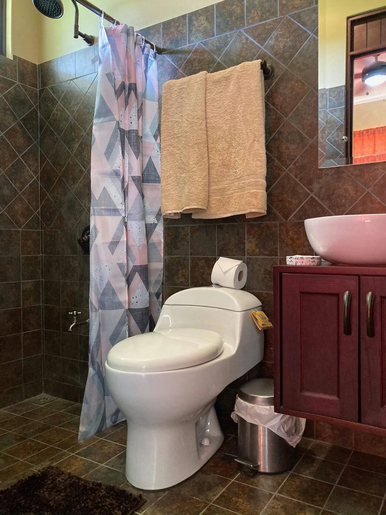 A tiled bathroom with a shower curtain, toilet, and sink vanity.