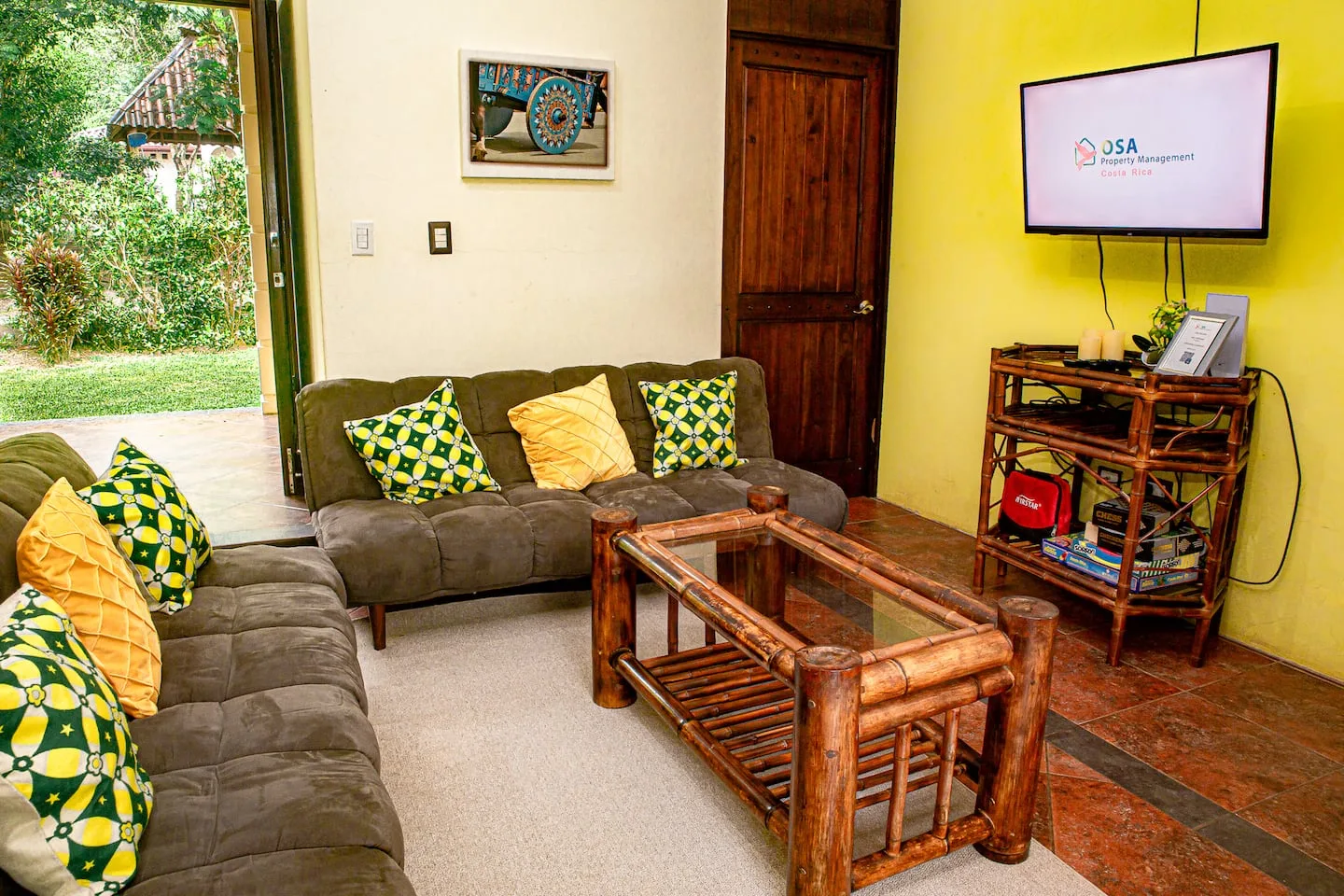 A living room with cushioned seating, a wooden coffee table, and a wall-mounted television.