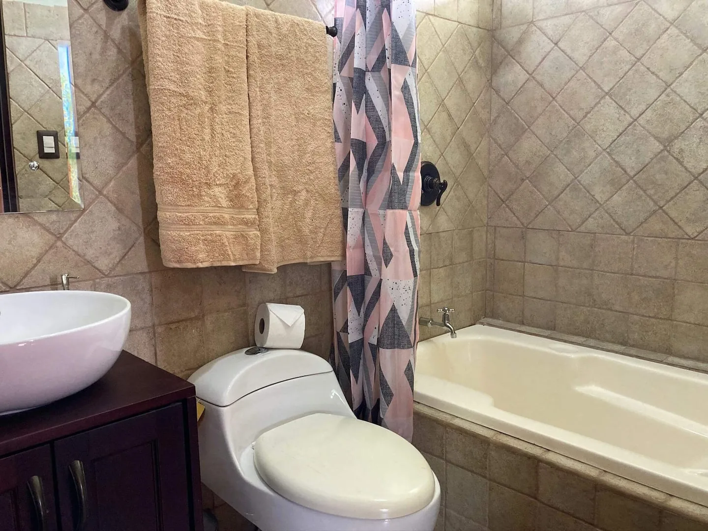 A tiled bathroom with a bathtub, toilet, and sink.