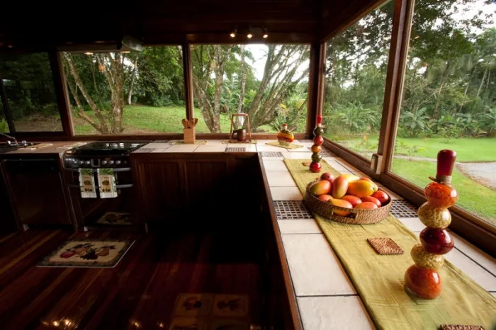 A kitchen counter overlooks a green garden through wide windows.