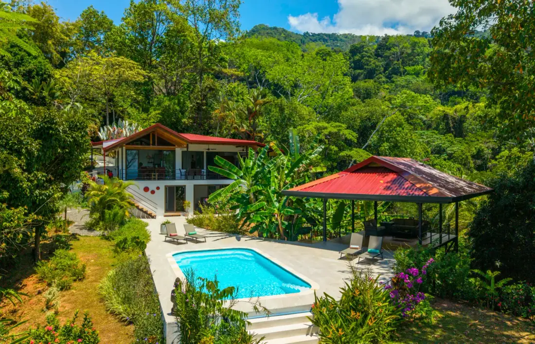 A pool and open-sided pavilion sit among lush tropical greenery.