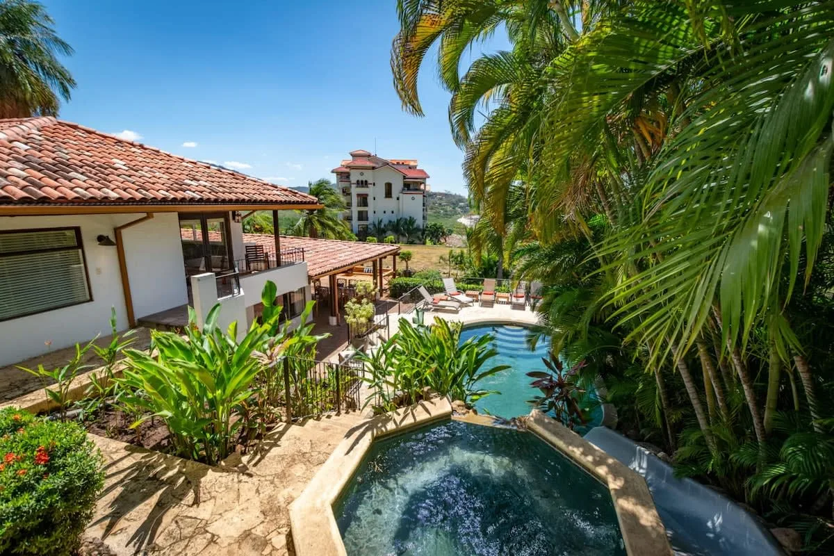 A tropical courtyard with a swimming pool and a small bubbling spa.