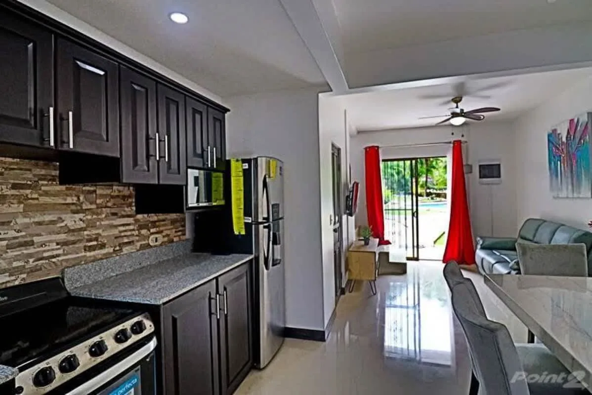 A kitchen opens into a living and dining area with sliding glass doors.