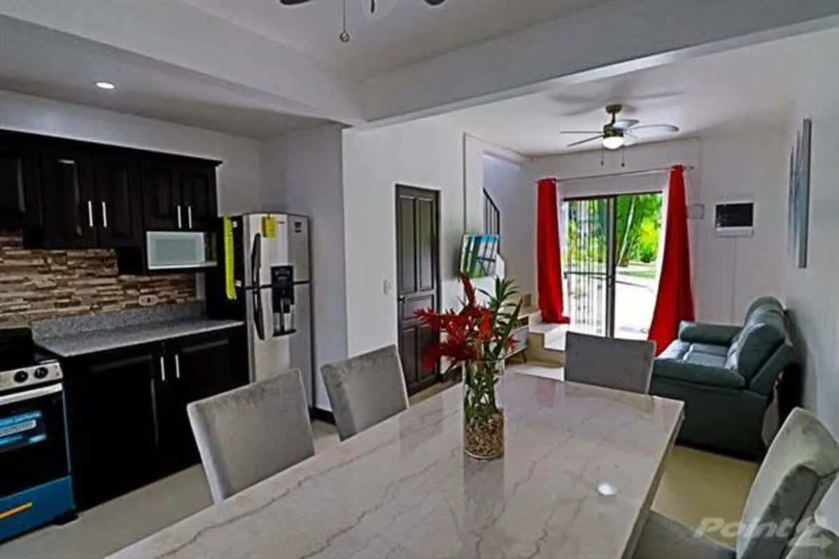 An open-plan kitchen and dining area leads into a living room with sliding glass doors.