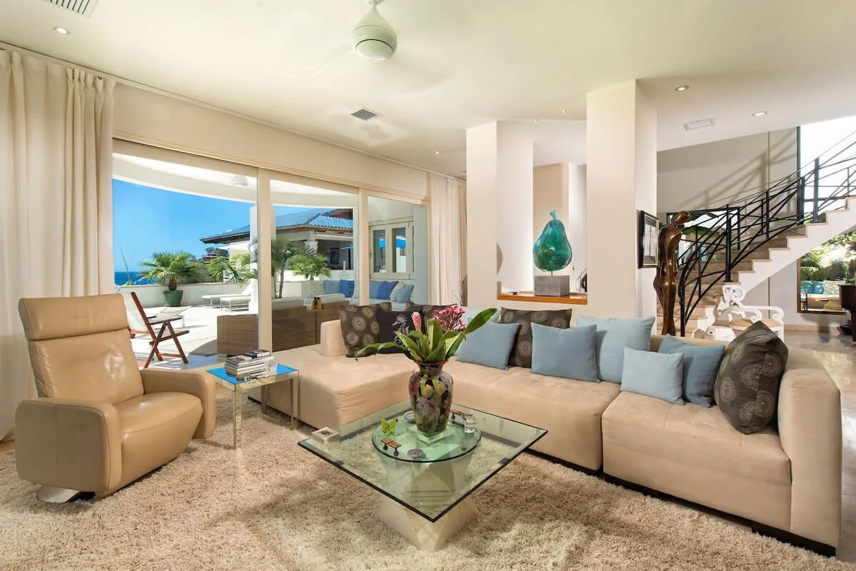 A bright living room with a large seating area and glass doors opening onto a patio.