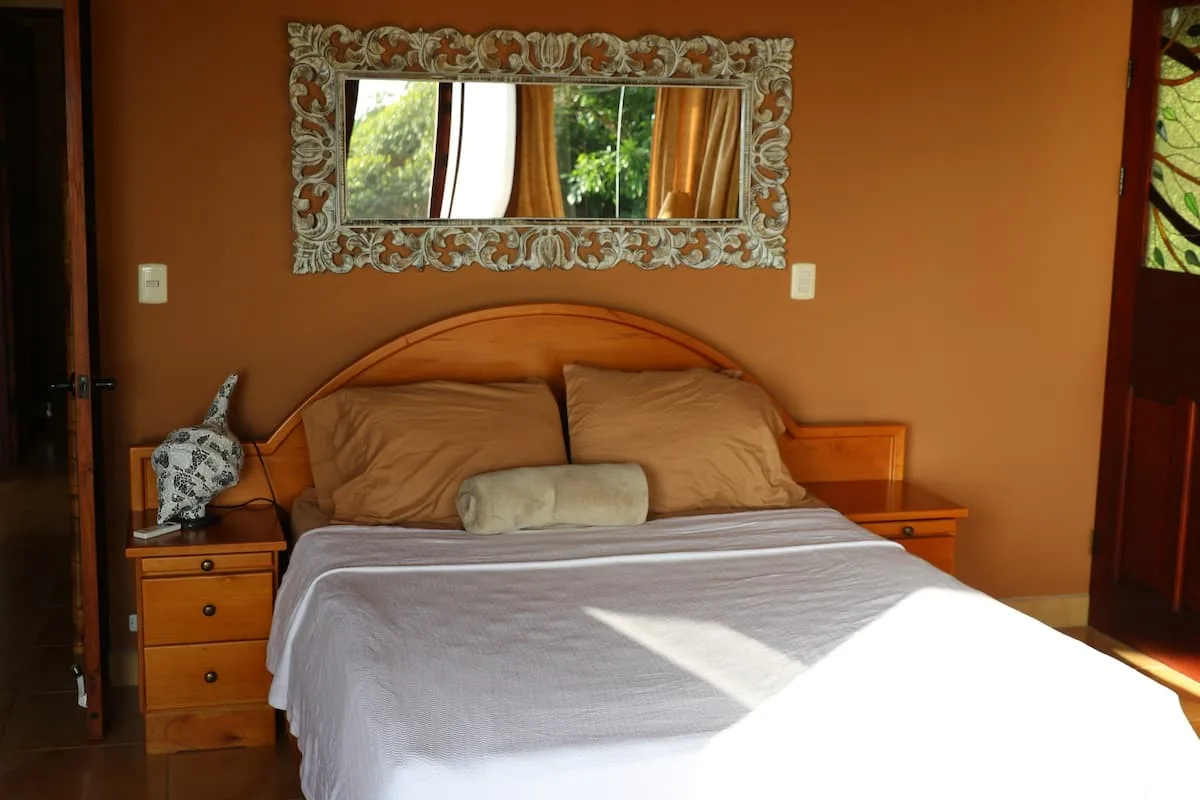 A bedroom with a made bed, matching bedside tables, and a wall mirror.