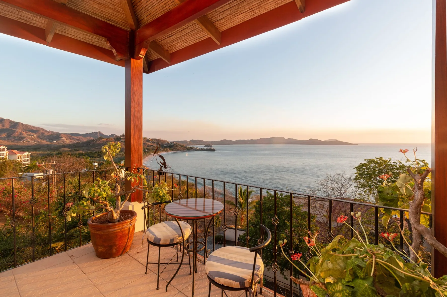 A covered terrace with seating overlooks the sea and distant coastline.