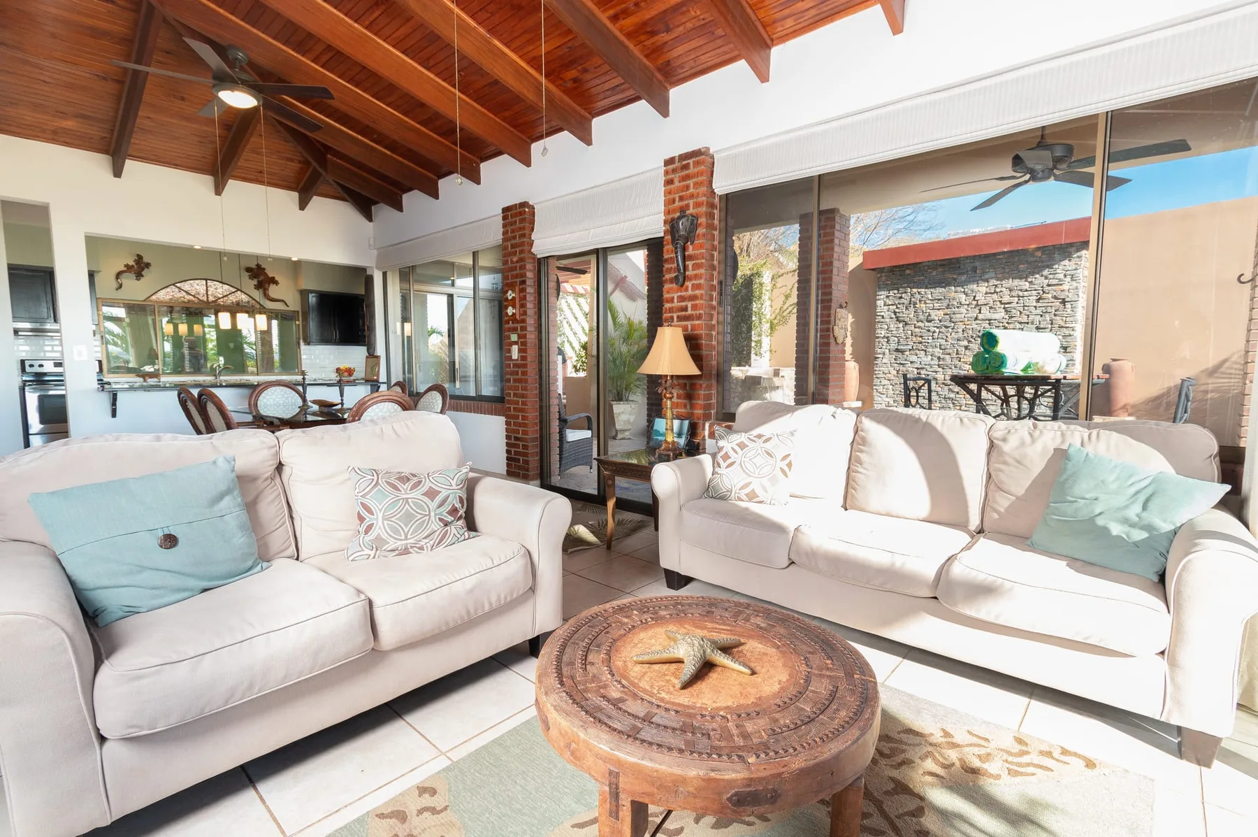 A bright living room with light seating and a round wooden coffee table.