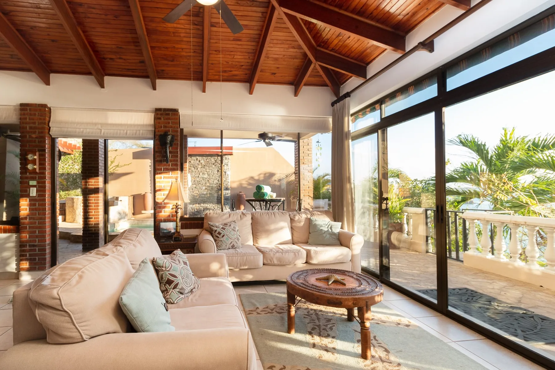 A bright living room with cushioned seating beside large glass doors.