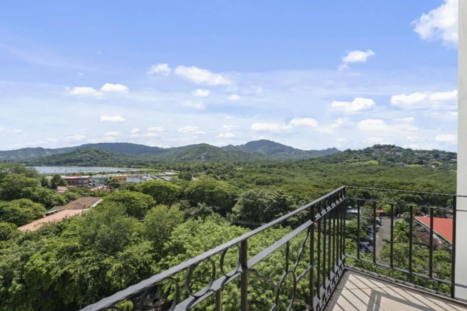 A balcony overlooks a broad expanse of green trees and distant hills.