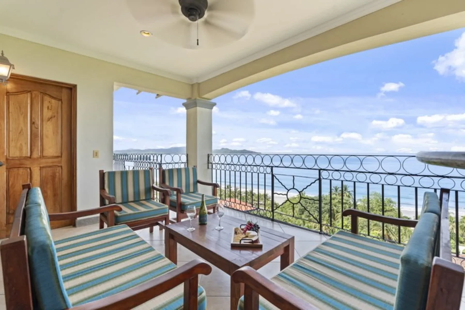 A covered terrace with striped seating and a view of the water.