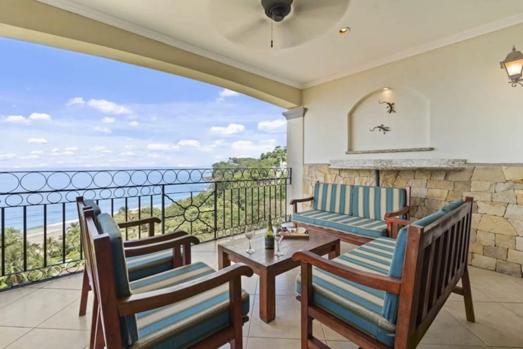 A covered balcony seating area overlooks a green landscape and distant water.