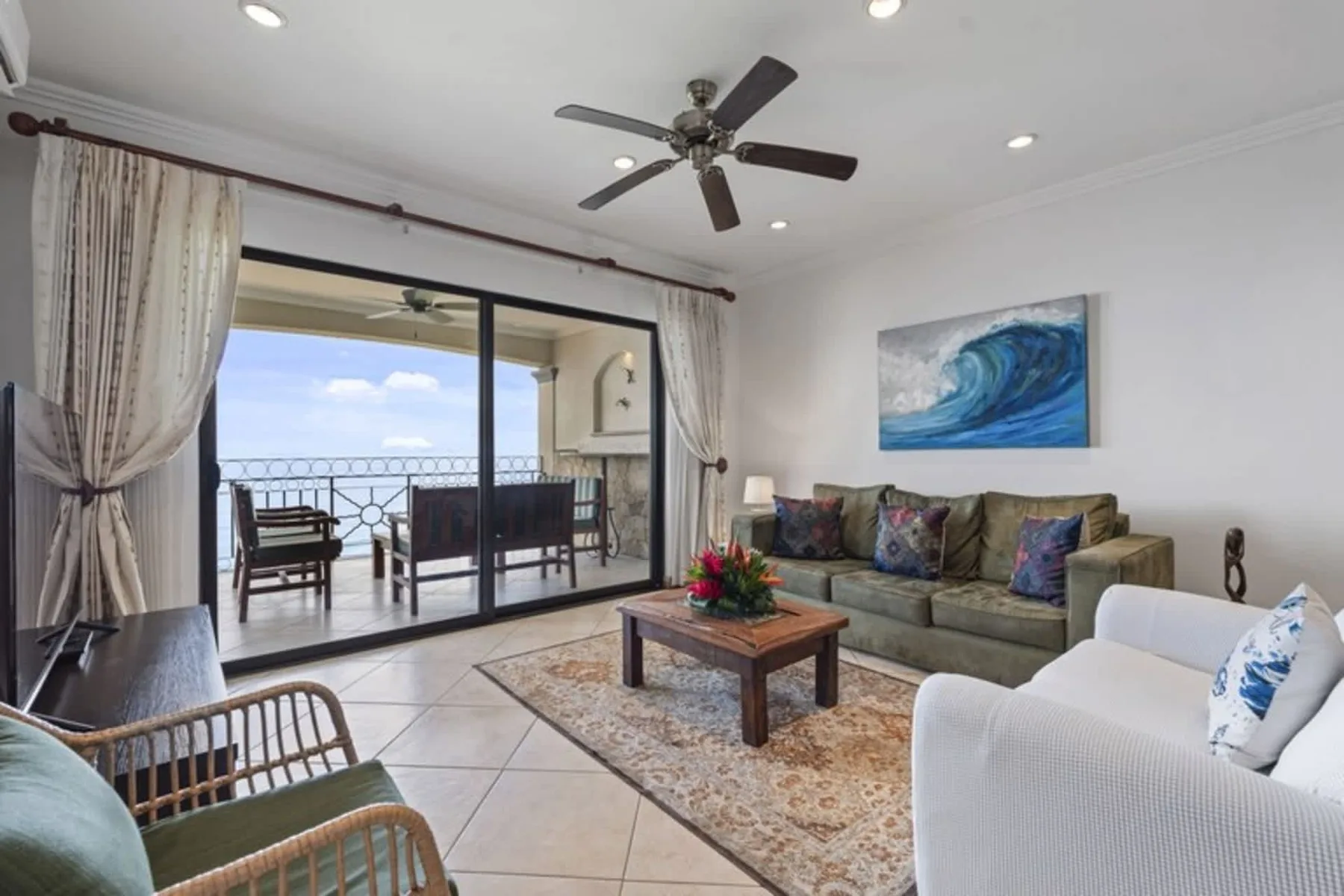 A living room with seating around a coffee table beside sliding glass doors.