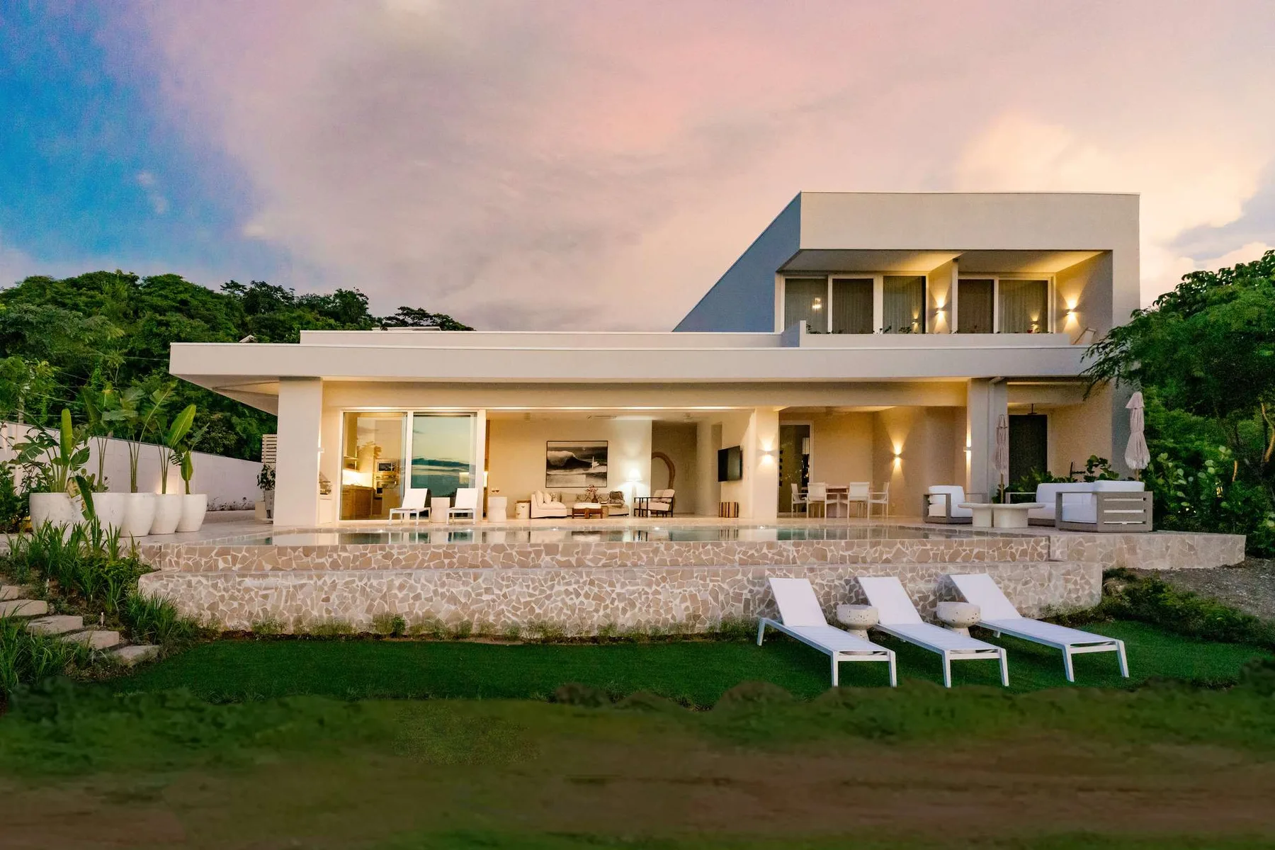 A modern house with a broad terrace overlooking a green lawn.