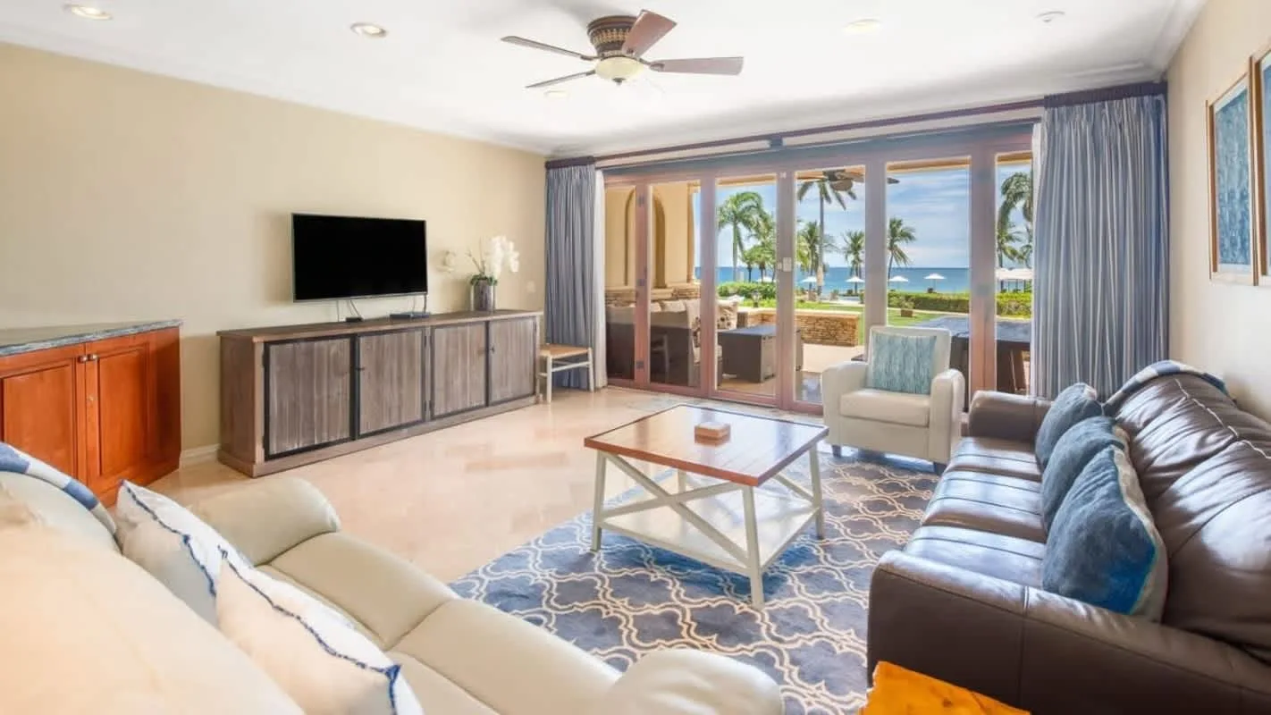 A bright living room with seating, a coffee table, and sliding glass doors.