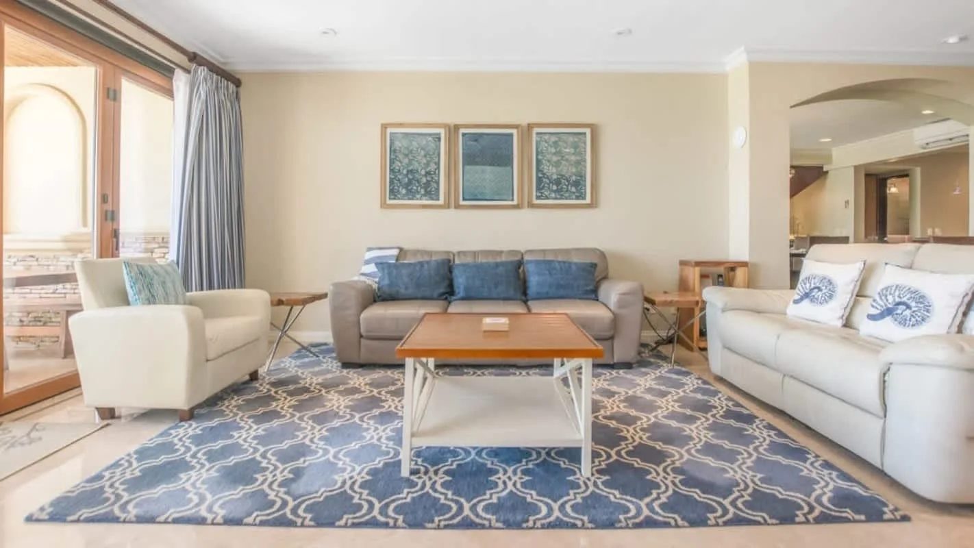 A living room with seating around a coffee table on a patterned rug.